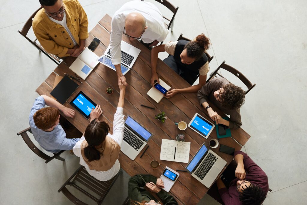 Menschen sitzen am Tisch und planen etwas am Notebook